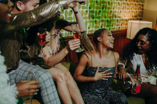 A joyful party scene featuring friends laughing and enjoying drinks indoors.